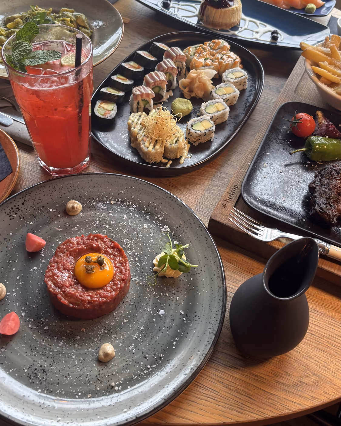 Klassisches Beef Tatar mit Eidotter, dahinter Maki und Inside-out-Rolls in der Augenweide Wien